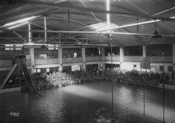 Black-and-white photo of Spruce Pool when it was an indoor pool, with a crowd of swimmers around the water